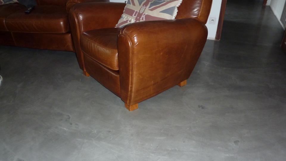 Ce fauteuil Club est mis en valeur grâce au sol en béton ciré qui reflète la lumière